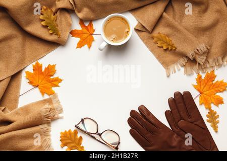 Concept d'automne.Foulard beige cachemire tasse à café verres gants en cuir avec feuilles de chêne et d'érable sur fond gris.Espace de copie de la vue de dessus de la pose à plat Banque D'Images