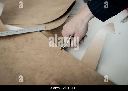 fabriquer des vêtements. tailleur avec des ciseaux fait des serifs sur le croquis Banque D'Images