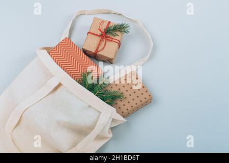 Boîtes-cadeaux durables de Noël en sac en coton écologique avec branches en sapin, sur fond bleu.Noël zéro gaspillage.Flat lay, vue de dessus.Qual. Élevée Banque D'Images