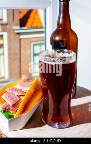 Boire de la bière foncée avec sandwich au poisson fumé à l'anguille avec vue sur la rue dans la vieille ville de Zierikzee, Zeeland, pays-Bas, gros plan Banque D'Images