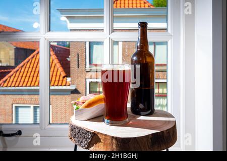 Boire de la bière foncée avec sandwich au poisson fumé à l'anguille avec vue sur la rue dans la vieille ville de Zierikzee, Zeeland, pays-Bas, gros plan Banque D'Images