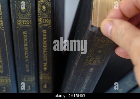 Flou artistique, bruit, flou, effet de grain.Un homme prend un livre de Fyodor Dostoevsky de la bibliothèque.Une collection de plusieurs volumes d'œuvres de la célèbre Russi Banque D'Images