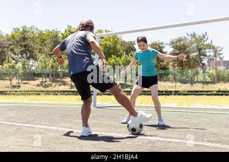 Couple d'âge mûr heureux jouant au football en plein air Banque D'Images