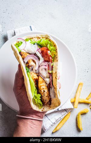 Porte-mains des gyroscopes de poulet avec légumes, frites et sauce tzatziki, vue du dessus.Cuisine grecque. Banque D'Images