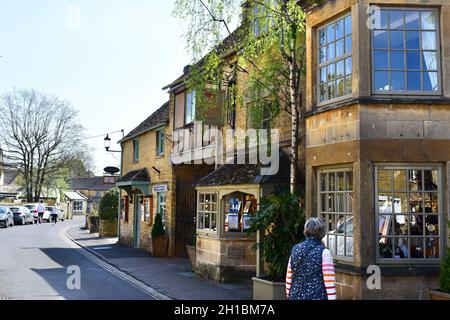 Vue sur les boutiques et les cafés le long de l'une des rues du centre de ce magnifique village de Cotswold. Banque D'Images