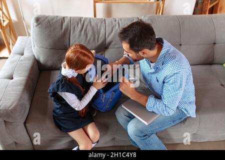 Vue de dessus image de père et de fille, un élève empaquant le sac à dos de l'école ensemble.Préparation scolaire Banque D'Images