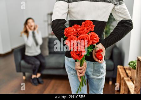 Homme femme suprising avec bouquet de roses et anneau d'engagement à la maison. Banque D'Images