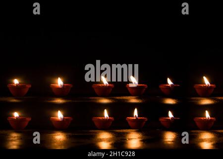 Groupe de diyas décorés sur fond noir pendant Diwali Banque D'Images