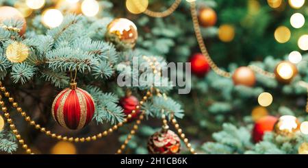 Bannière floue Noël et nouvel an 2022.Décoration festive d'épicéa bleu de montagne à l'extérieur.Boules rouges, guirlande lumineuse, perles d'or sur vert avec Banque D'Images