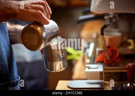 Un barman prépare un lait pour faire un espresso aromatique et parfumé dans l'appareil.Café, boissons, bar Banque D'Images