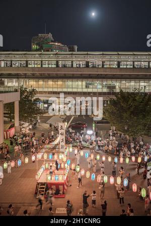 Vue sur la place en face de la gare de Nippori décorée pour le festival d'Obo avec une tour yagura illuminée de lanternes en papier où un g Banque D'Images