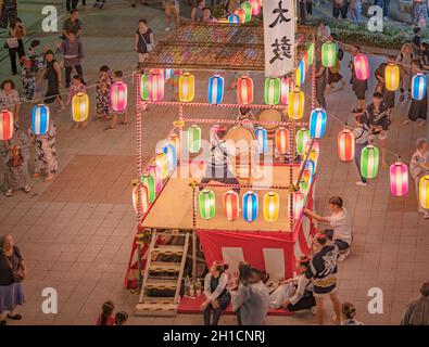 Vue sur la place en face de la gare de Nippori décorée pour le festival d'Obo avec une tour yagura illuminée de lanternes en papier où un g Banque D'Images