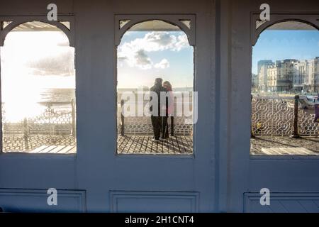 Vue par une fenêtre d'un couple qui donne sur la mer à Brighton Pier Banque D'Images