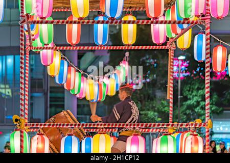 Vue sur la place en face de la gare de Nippori décorée pour le festival d'Obo avec une tour yagura illuminée de lanternes en papier où un m Banque D'Images