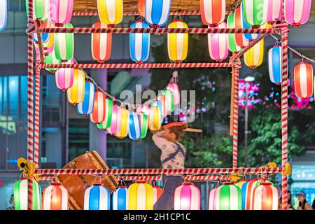 Vue sur la place en face de la gare de Nippori décorée pour le festival d'Obo avec une tour yagura illuminée de lanternes en papier où un g Banque D'Images