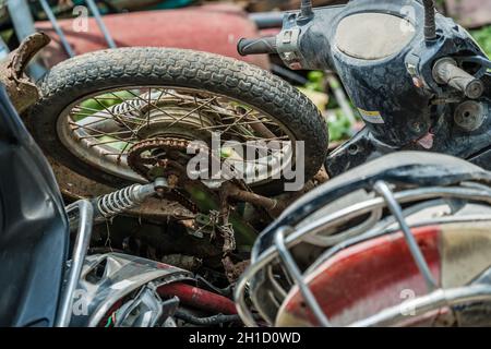 Yangshuo, Chine - Août 2019 : Utilisé, vieux, endommagé et mis au rebut des motos, motos et scooters empilés dans la cour à l'extérieur du recyclage des métaux p Banque D'Images