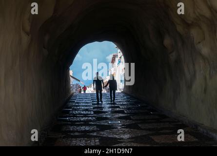 Silhouette d'un couple marchant à travers un tunnel piétonnier à la plage d'Albufeira dans l'Algarve, au Portugal Banque D'Images