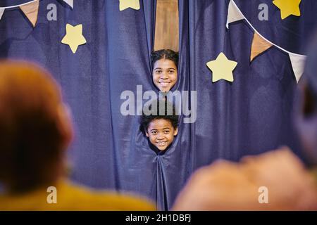 Des enfants africains heureux qui sortent des coulisses, montrent des performances aux adultes Banque D'Images