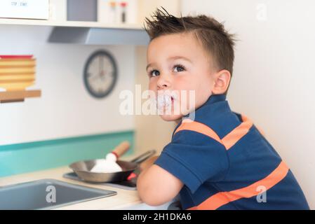 Petit garçon joue le jeu comme s'il était un cuisinier ou un boulanger dans un jouet pour enfants cuisine . Banque D'Images