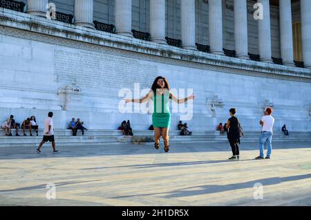 Jeune fille gaie dans une robe verte sautant sur l'arrière-plan des colonnes de marbre de l'Altare della Patria également connu sous le nom de Vittorio Emanuele II Mon Banque D'Images