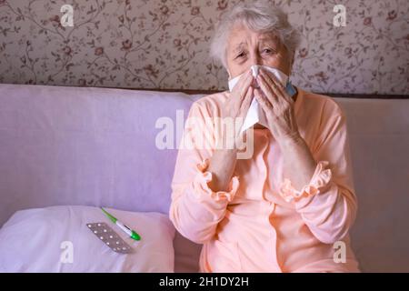Une femme mûre malade couverte d'une couverture soufflant nez éternuant dans les tissus souffrent d'allergie ou de grippe.Le Covid-19, santé, sécurité et conc. Pandémique Banque D'Images