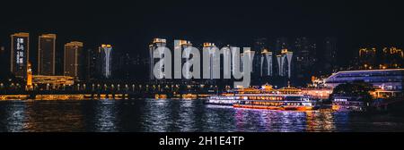 Chongqing, Chine - août 2019 : vue nocturne sur la ville de Chongqing illuminée sur la rivière Jialing et Yangtze avec bateau de luxe à passagers de croisière amarré sur t Banque D'Images