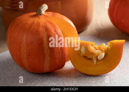 Des pumkins Hokkaido entiers orange et une pièce avec des graines gros plan Banque D'Images