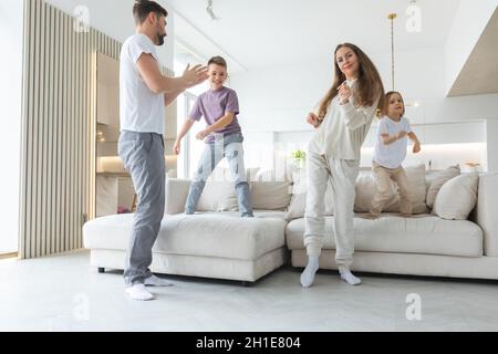 Famille s'amuser à la maison. Couple marié avec jeunes enfants dansant dans la salle de séjour. Concept de famille heureuse passer du temps ensemble Banque D'Images