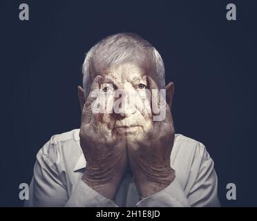 Portrait d'un homme âgé avec le visage fermé par les mains sur le noir.Collage.Concept d'horreur.Concepts Covid-19 ou coronavirus Banque D'Images