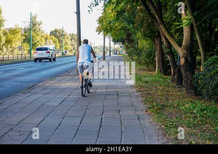 POZNAN, POLOGNE - 06 septembre 2013 : vue arrière d'une promenade masculine avec son vélo sur un trottoir Banque D'Images