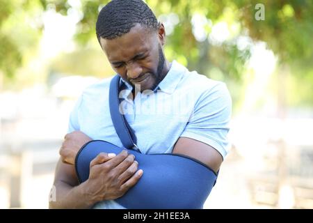 Homme stressé à peau noire avec bras en suspension se plaignant dans un parc Banque D'Images