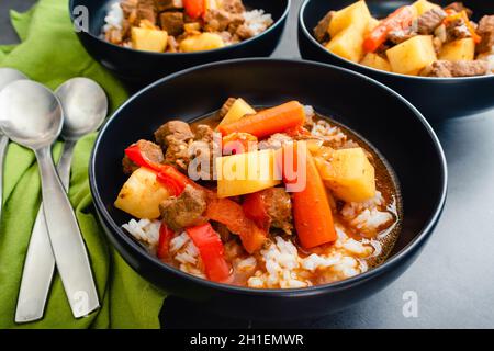 Bols de ragoût de bœuf philippin Mechado servis sur du riz blanc : bœuf braisé à la sauce tomate avec des morceaux de pommes de terre et de carottes Banque D'Images