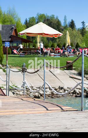 Niedzica; Pologne - 18 mai; 2020: Touristes se reposant sur des chaises longues sur les rives du lac Czorsztyn à côté de la marina pour les bateaux touristiques Banque D'Images