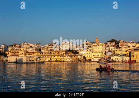 UDAIPUR, INDE - 23 NOVEMBRE 2012 : Palais de la ville et bateau touristique sur le lac Pichola au coucher du soleil.Udaipur, Rajasthan, Inde Banque D'Images