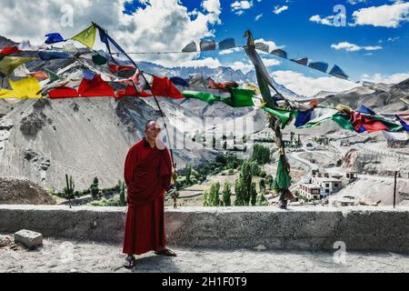 LAMAYURU, INDE - 10 SEPTEMBRE 2011 : moine bouddhiste debout à l'extérieur avec des drapeaux de prière lugta dans le monastère bouddhiste Lamayuru gompa à Ladakh, Inde Banque D'Images