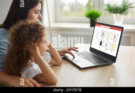 La mère et l'enfant magasinent pour de nouveaux vêtements dans un magasin de vêtements Internet pour toute la famille Banque D'Images