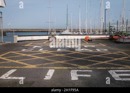 Howth près de Dublin, Irlande - 15 février 2019 : garder la peinture de bateau de vie claire sur le bitume d'une zone d'entretien et de soin de bateau dans le port sur une étendue Banque D'Images