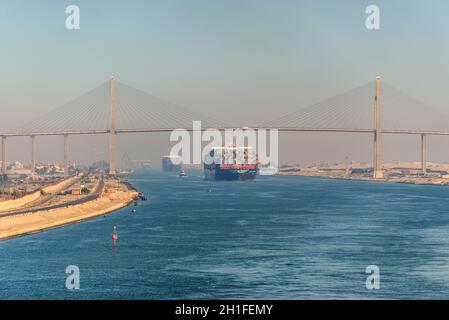 El Qantara, Egypte - Novembre 5, 2017 : conteneurs navires passant dans le canal de Suez en Égypte. Brume de sable La paix Moubarak Bridge est un pont routier Banque D'Images