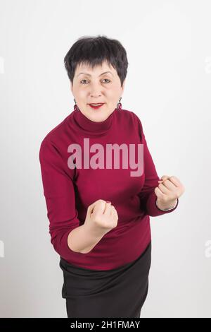 Photo de la femme en colère frobas visage, montre poing, a insatisfait expression du visage, porte des vêtements rouges décontractés, menaces sur quelque chose, isolé sur whi Banque D'Images