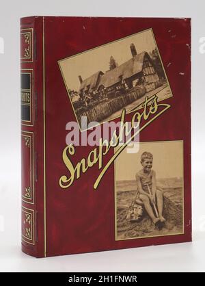 Instantanés, boîte métallique imprimée pour contenir des photos avec couvercle à charnière.années 1930.Photographie du cottage de chaume et du jeune garçon sur le château de sable avec seau et bêche.Britannique, fabricant inconnu. Banque D'Images