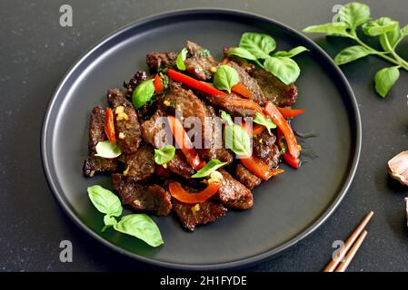 Sauté de bœuf thaïlandais au poivre et au basilic sur l'assiette, vue rapprochée Banque D'Images