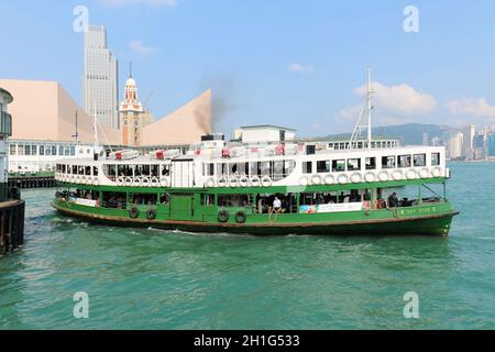 Hong Kong, Chine - 30 avril 2017 : les touristes apprécient la navigation sur le bateau à vapeur traditionnel Star Ferry dans le port de Victoria avec la célèbre ligne d'horizon à l'arrière en H Banque D'Images