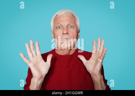 Homme âgé avec expression de l'étonnement sur fond bleu au studio Banque D'Images