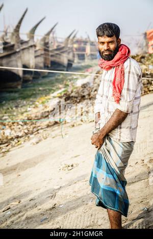 Chittagong, Bangladesh, 23 décembre 2017 : portrait d'un pêcheur d'âge moyen avec des bateaux de pêche traditionnels en arrière-plan Banque D'Images