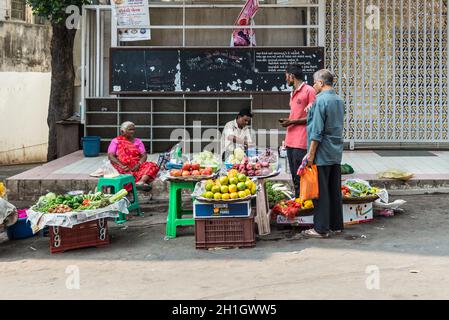 Mumbai, Inde - 22 novembre 2019 : une femme et un homme indiens vendent des fruits et des légumes sur un marché de rue à Mumbai (connu en Inde sous le nom de Bombay). Banque D'Images