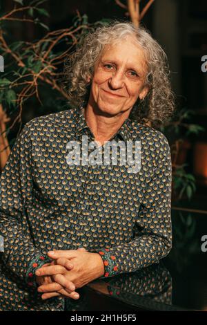 portrait d'un homme de 65 ans avec cheveux gris bouclés dans un t-shirt regarde l'appareil photo, sourit, artiste de profession, musicien, acteur. Banque D'Images