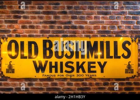 Bushmills, Irlande du Nord, août 2019 Old Bushmills Whiskey célèbre depuis plus de 300 ans signe sur le mur de brique rustique dans le centre des visiteurs et boutique de distillerie Banque D'Images