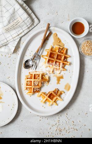 Gaufres belges ou bruxelloises au sirop d'érable et quinoa soufflé.Assiette presque vide avec de délicieuses gaufres bruxelleuses mangées. Banque D'Images