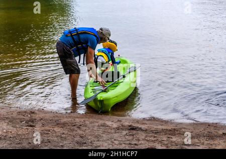 Grand-père et petit-fils assis dans un kayak pour naviguer le long le lac le long des rochers en kayak Banque D'Images