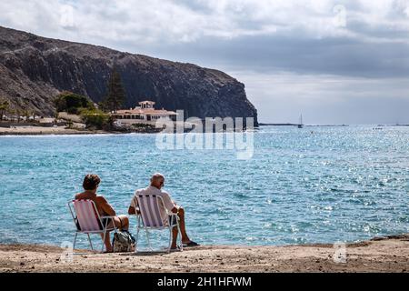 Los Cristianos, Ténérife, Espagne - 18 février 2019 : un couple de personnes âgées se repose sur des vacances, se reposant sur la rive de l'océan Atlantique, dans l'un des Banque D'Images